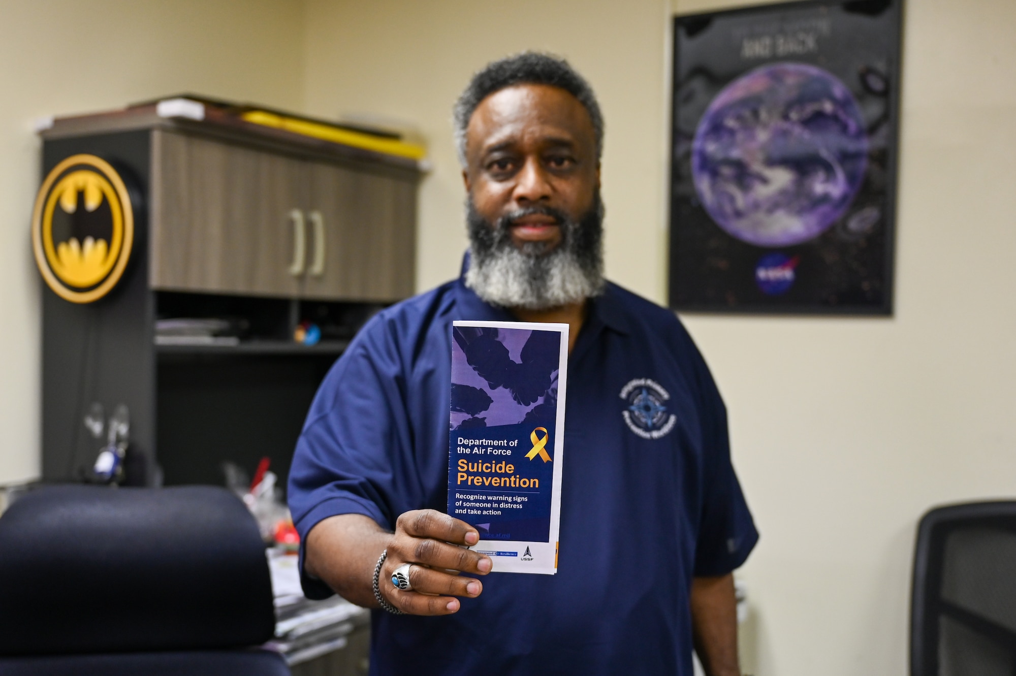 Wendell Browne, 97th Air Mobility Wing prevention specialist, holds up a suicide prevention brochure at Altus Air Force Base, Oklahoma, Aug. 21, 2024. Browne teaches suicide prevention classes throughout the year to encourage Airmen to care for and listen to their fellow wingmen. (U.S. Air Force photo by Senior Airman Kari Degraffenreed)
