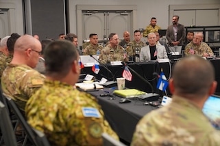 Military personnel sit around a table for a discussion.