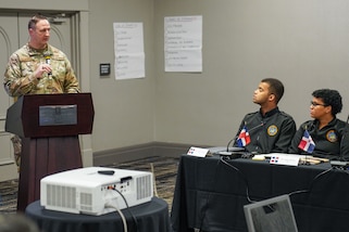 A military officer speaks from a podium.