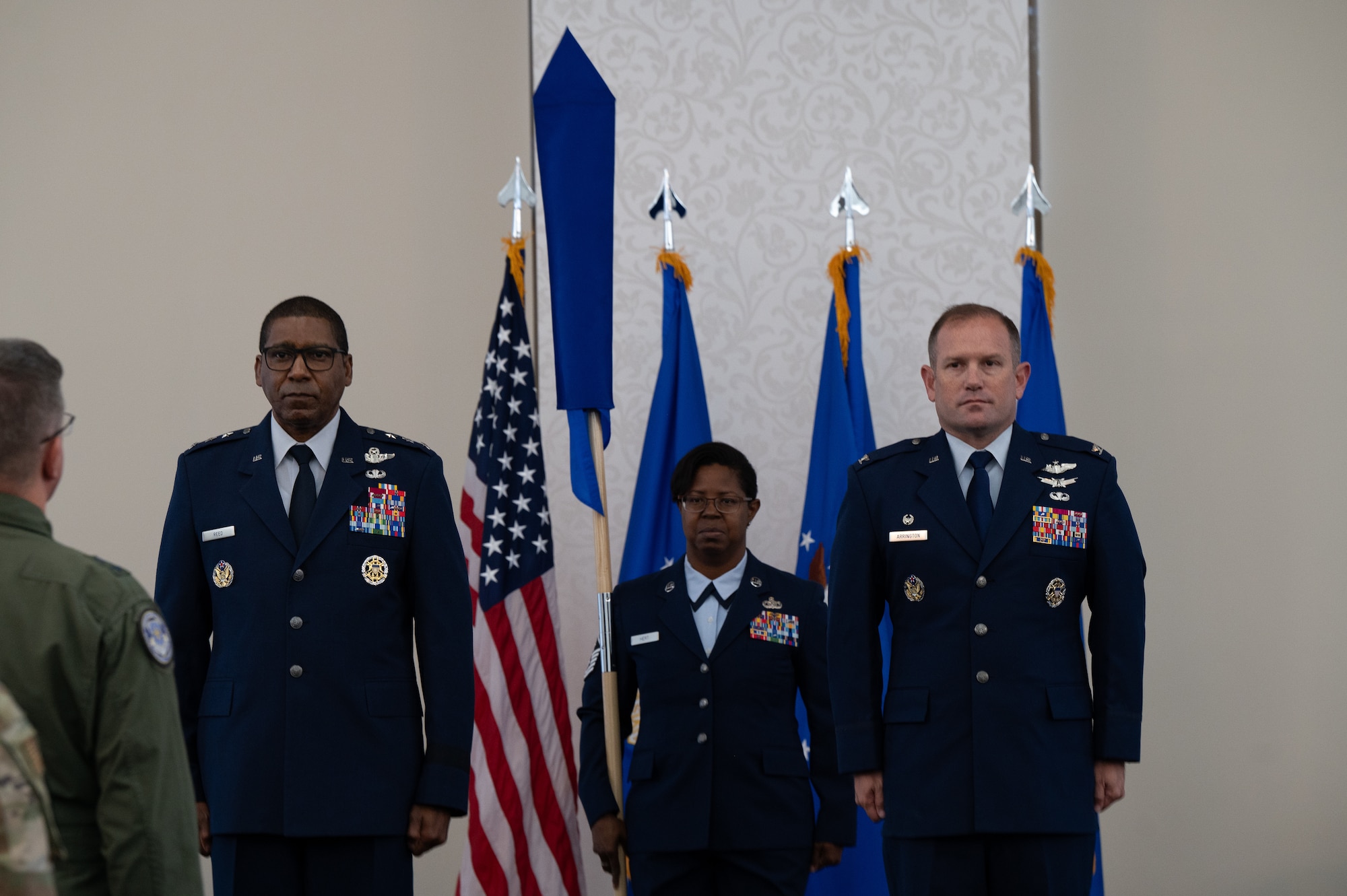 Reed, Hert and Arrington stand at attention, as Hert holds the guidon.