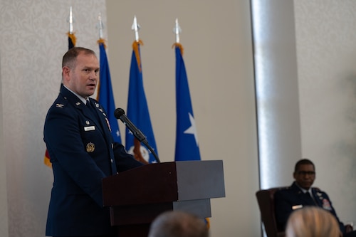 Arrington stands at a podium, speaking to the audience.