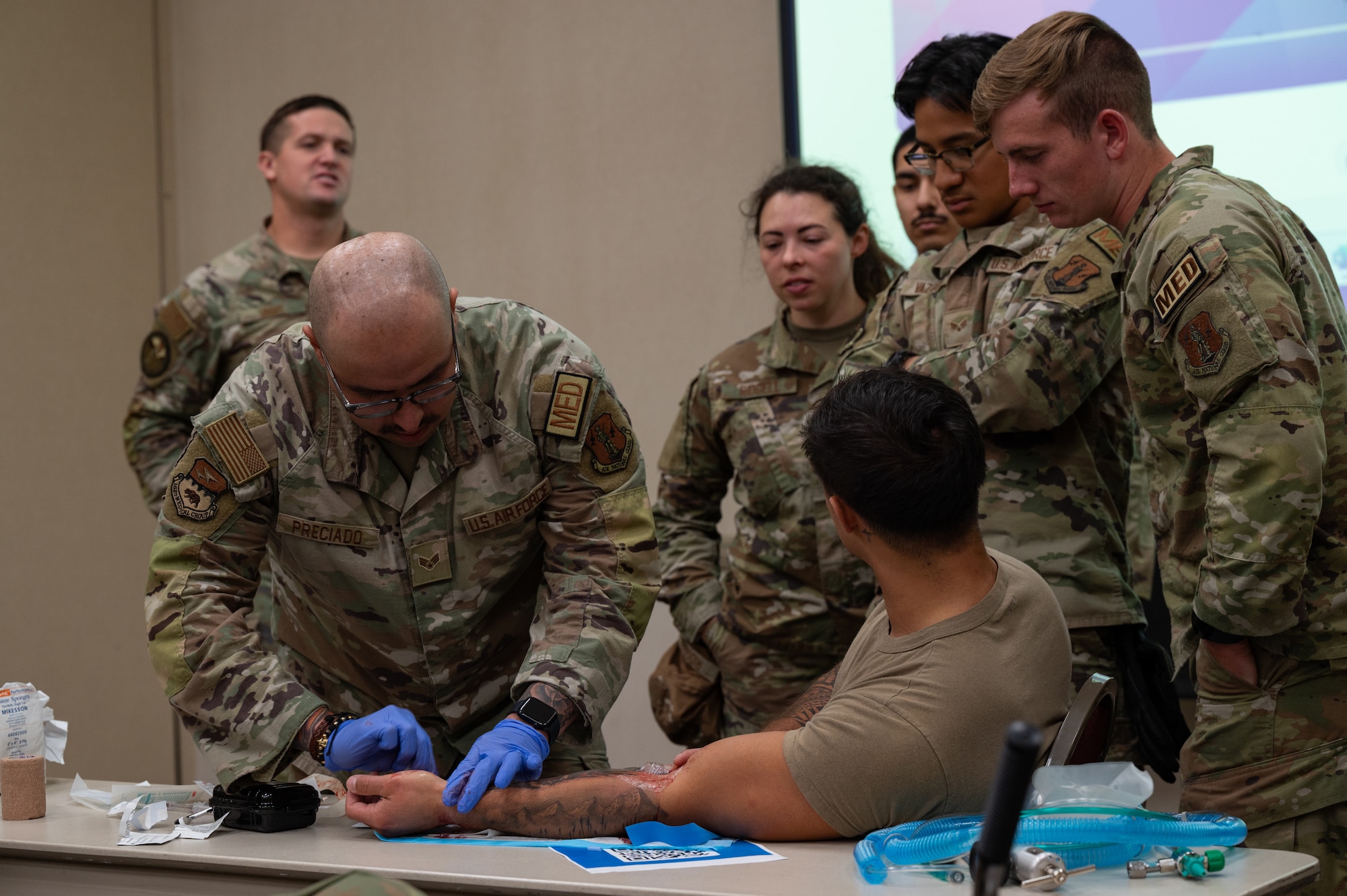 U.S. Senior Airman Roberto Preciado, left, aerospace medical service specialist, 163rd Attack Wing, California National Guard, demonstrates the placement of a ruggedized field IV during a MEDIC-X course at Alpena Combat Readiness Training Center, Alpena, Michigan, June 11, 2024. The course was part of Medical Readiness University, an Air National Guard-hosted two-week event offering multiple courses providing medical Airmen with hands-on operational training. (U.S. Air National Guard photo by Tech. Sgt. Sarah M. McClanahan)