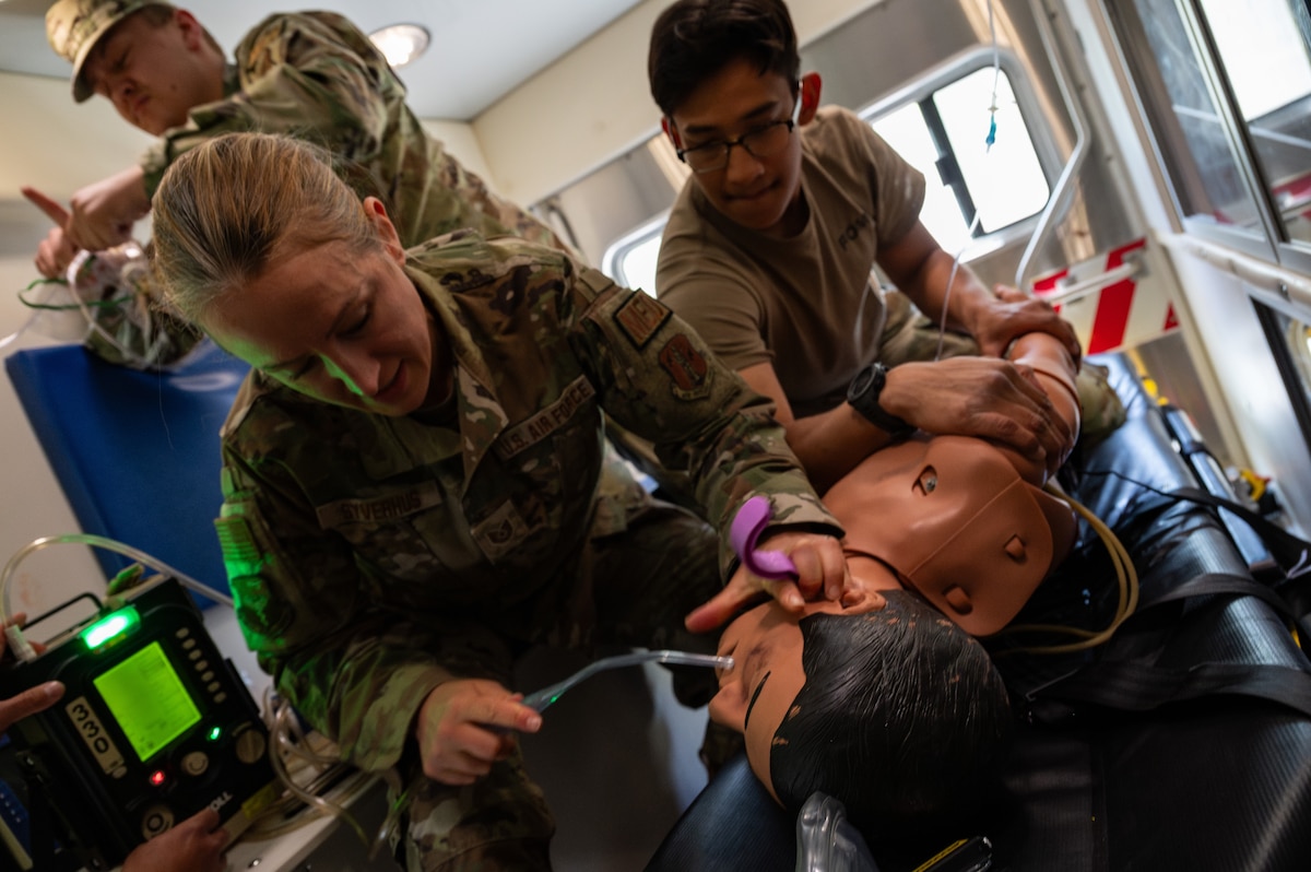 U.S. Air Force Tech. Sgt. Sara Syverhus, center, aerospace medical technician, 101st Aerial Refueling Wing, Maine National Guard, prepares to insert an oropharyngeal airway on a medical training manikin in a moving ambulance as part of a MEDIC-X course at Alpena Combat Readiness Training Center, Alpena, Michigan, June 11, 2024. The event was part of Medical Readiness University, an Air National Guard-hosted two-week event offering multiple courses providing medical Airmen hands-on operational training. (U.S. Air National Guard photo by Tech. Sgt. Sarah M. McClanahan)