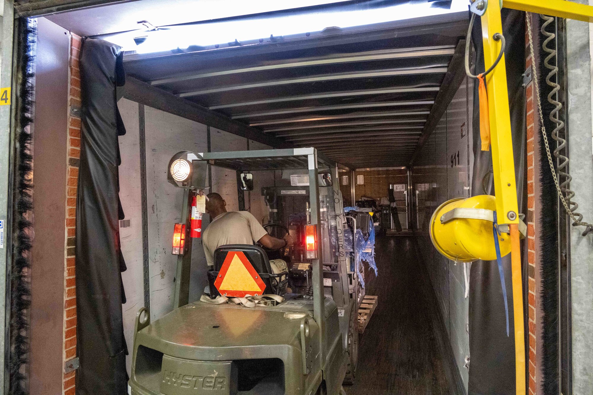 A forklift is driven into the back of a semi truck to deliver its pallet.