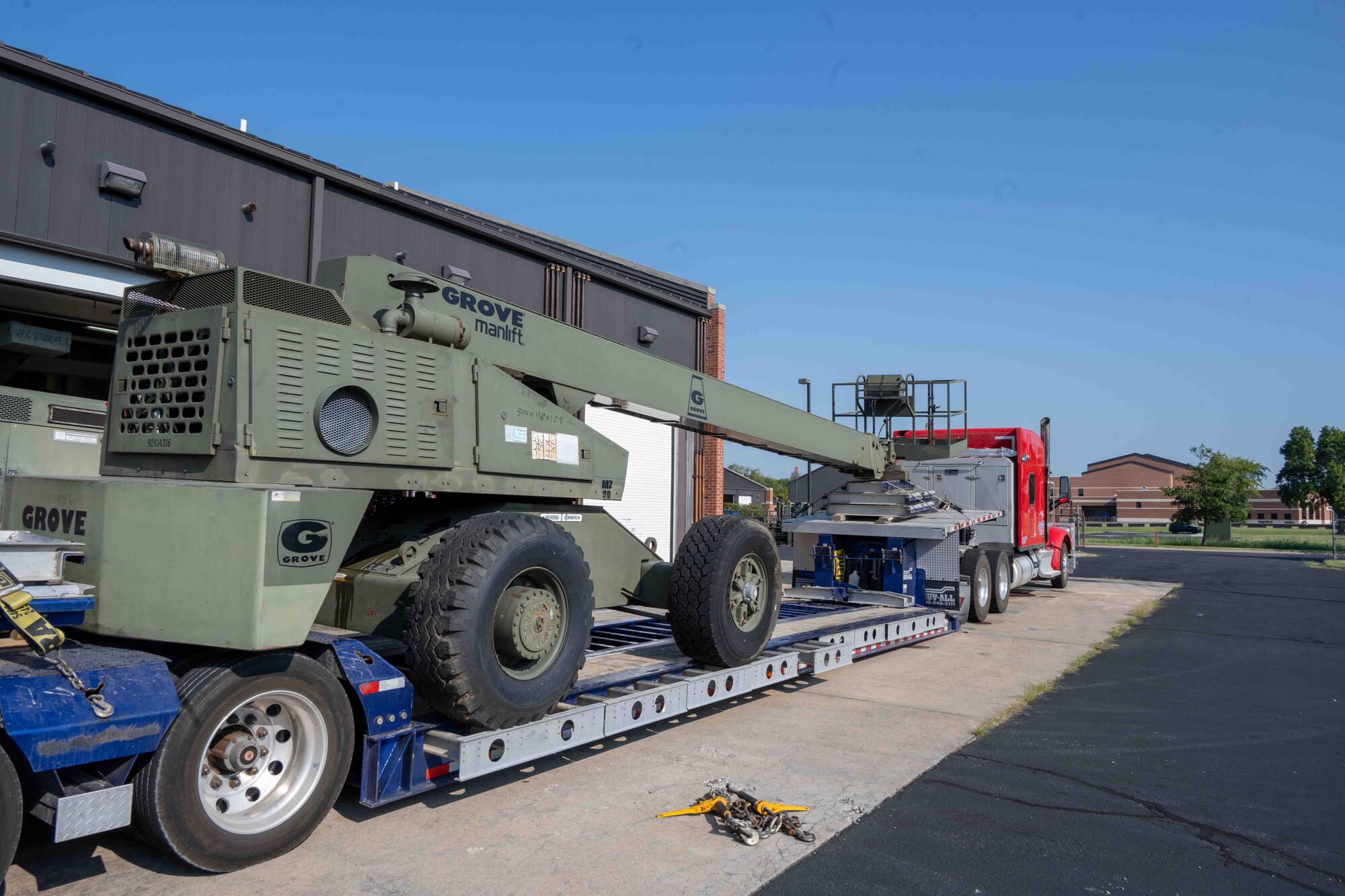 A manlift sits on the flatbed of a semi ready to drive away.