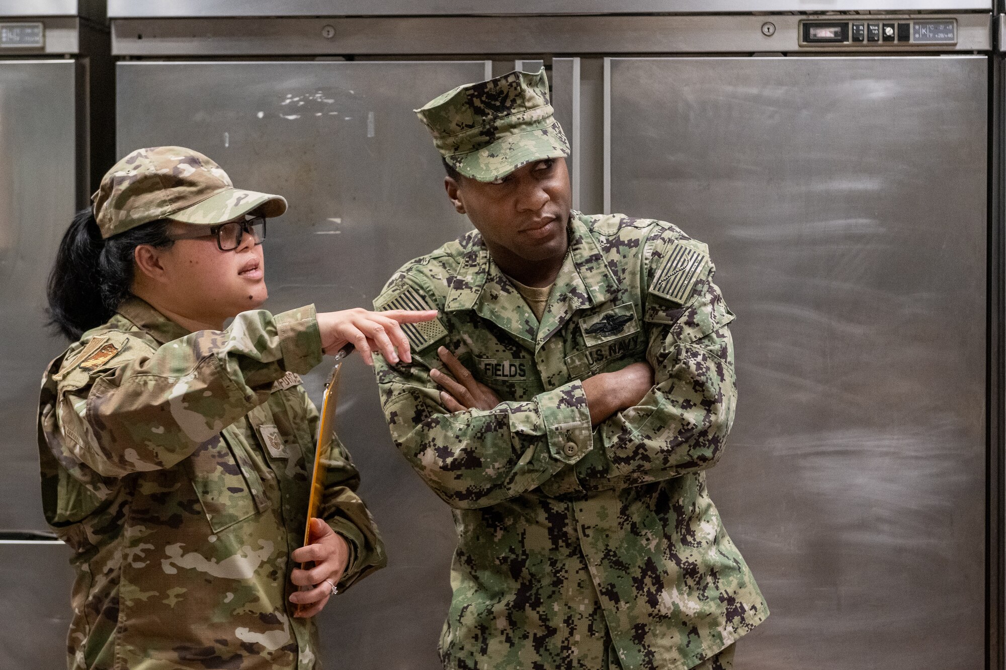 Two U.S. military members discuss a base food court safety inspection.