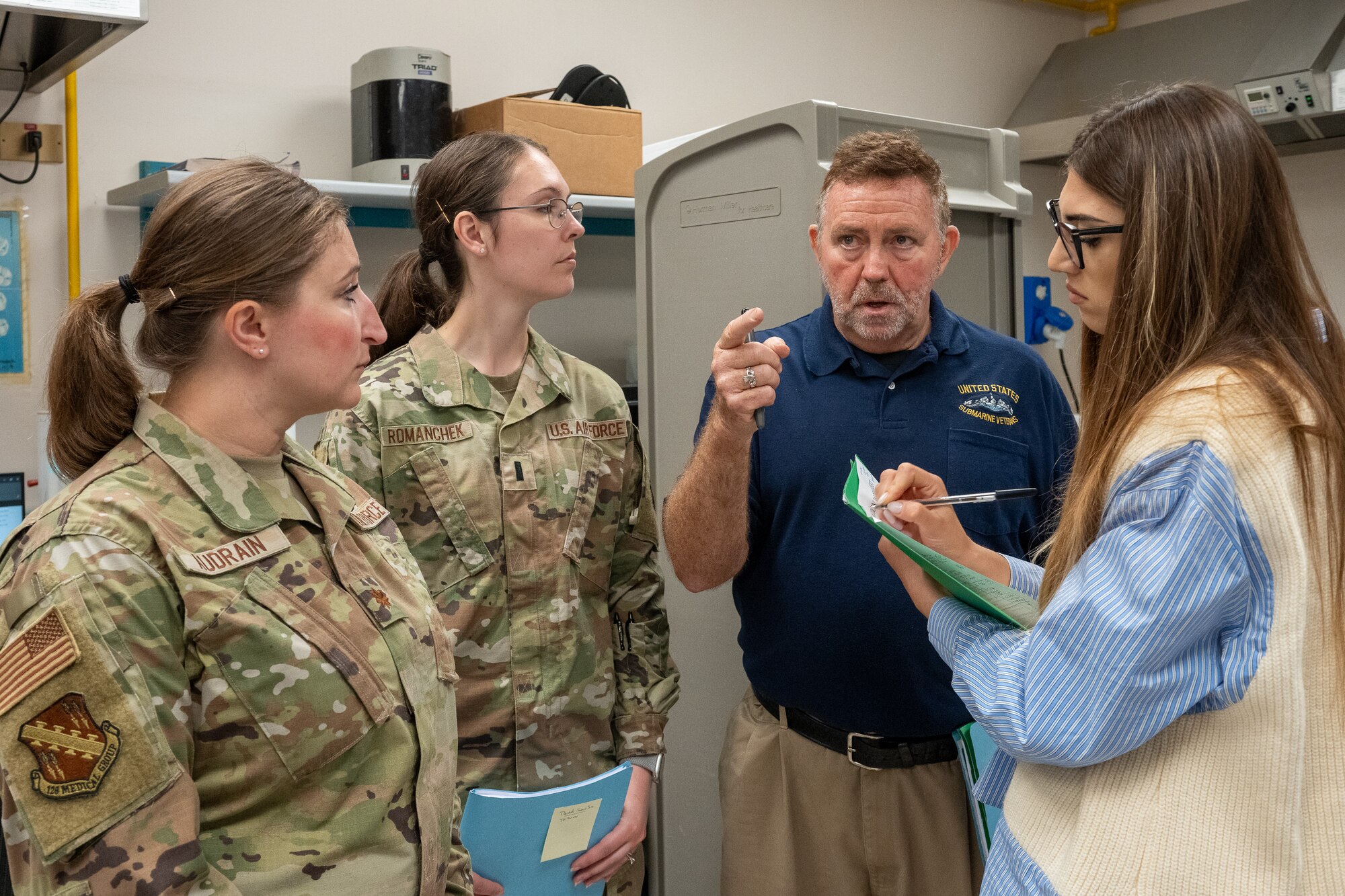 A group of 3 bioenvironmental engineers discuss noise levels with an industrial hygienist in a dental lab.