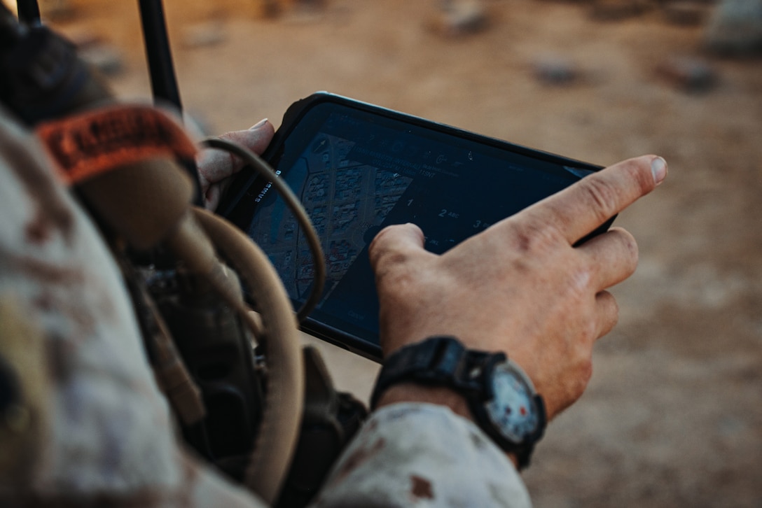 A U.S. Marine with Tactical Training and Exercise Control Group, Marine Air-Ground Task Force Training Command, Marine Corps Air-Ground Combat Center, uses a tablet to plot on a map during an Adversary Force Exercise as part of Service-Level Training Exercise 5-24 at Range 220, MCAGCC, Twentynine Palms, California, Aug. 6, 2024. TTECG has supported the Fleet Marine Force through various exercises including the SLTE Program and continue to ensure safety throughout every training event. SLTE 5-24 is purpose built to train, develop, and validate the Infantry Battalion Experiment as part of a larger MAGTF operation as a Stand-in Force across a contested multi-domain distributed environment. (U.S. Marine Corps photo by Cpl. Hunter Wagner)