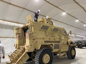 A person stands atop a armored vehicle.