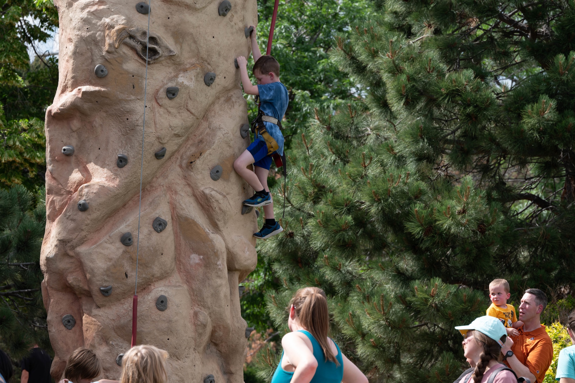 A boy is climbing a bouldering rock while at Patriot Fest