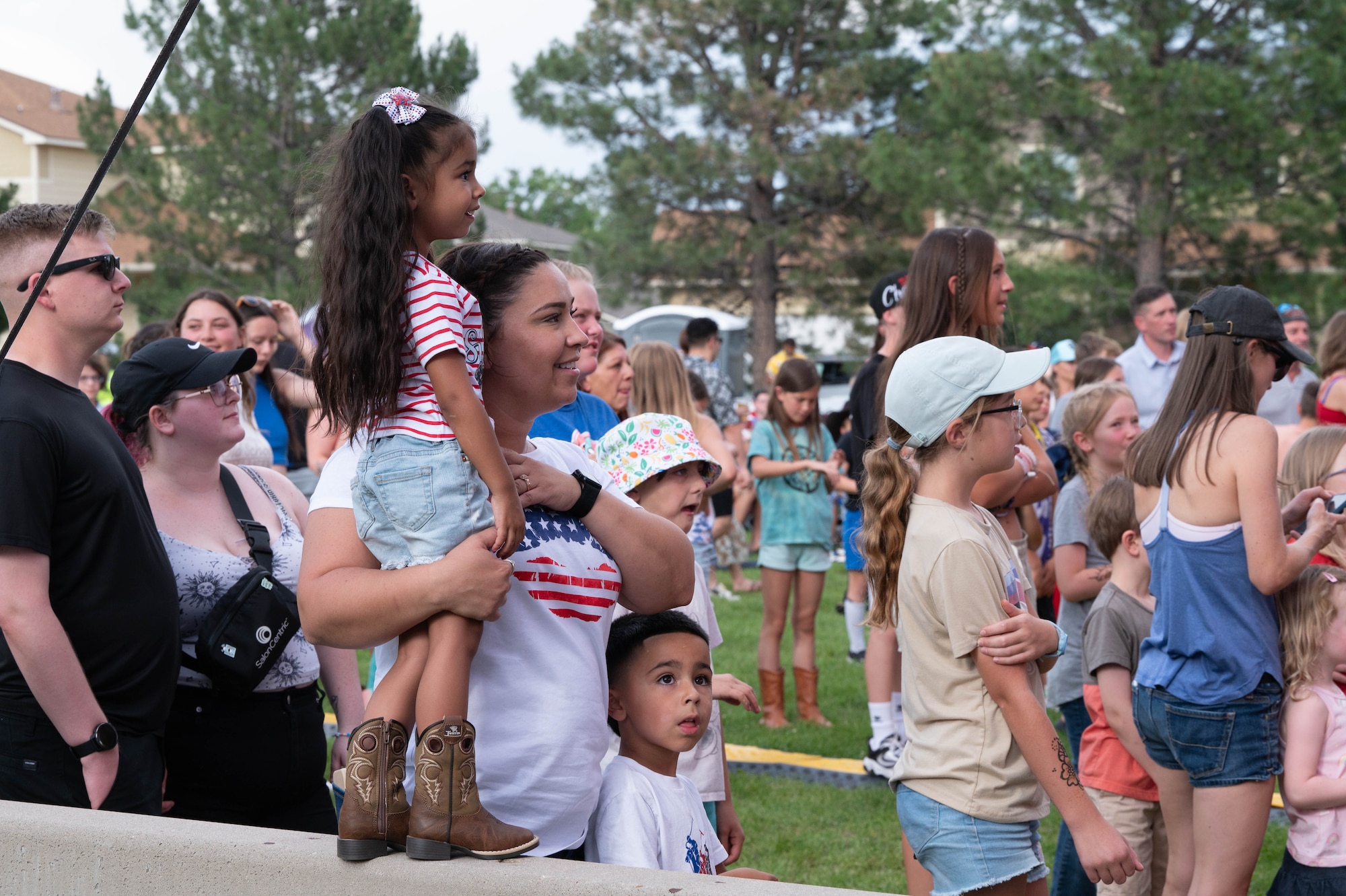 A mother and her children stand next to the stage as artists are performing.