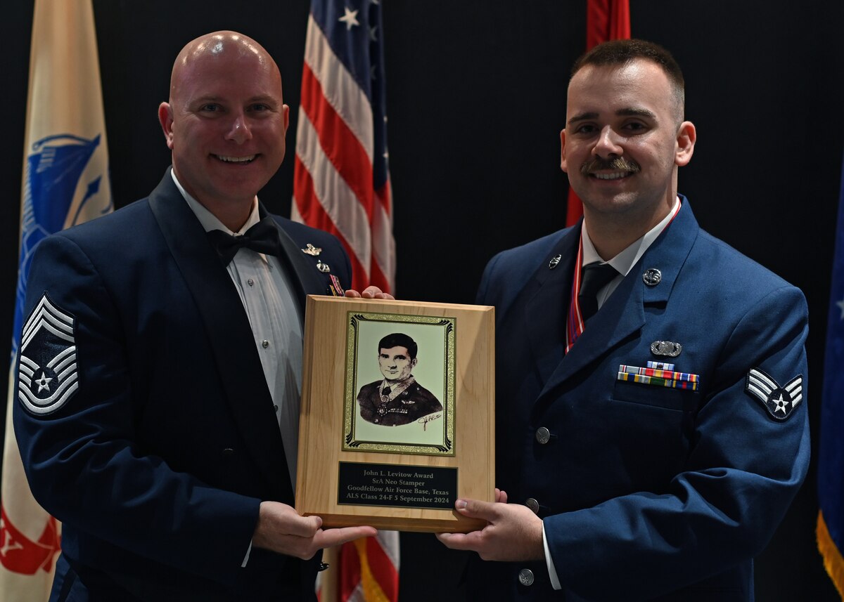 U.S. Air Force Chief Master Sgt. Kenneth Wilson, 47th Operations Group senior enlisted leader, gives Senior Airman Neo Stamper, Airman Leadership School graduate, the John L. Levitow Award at the Airman Leadership School class 24-F graduation at the Powell Event Center, Goodfellow Air Force Base, Texas, Sept. 5, 2024. The John Levitow Award is the highest honor presented to an ALS graduate. (U.S. Air Force photo by Senior Airman Ethan Sherwood)