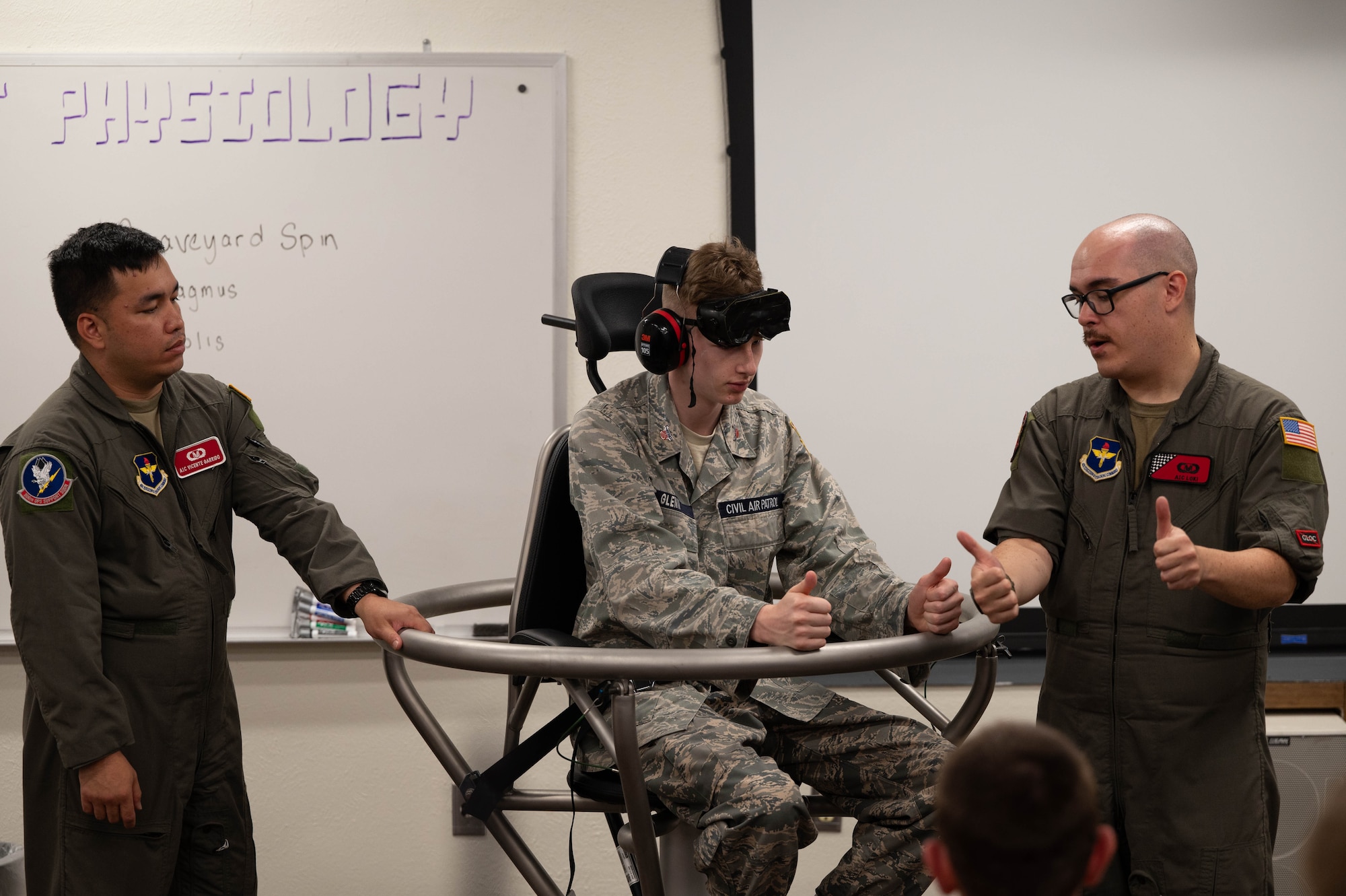 A cadet is being explained by instructors on what to expect as he sits on the Barany chair.