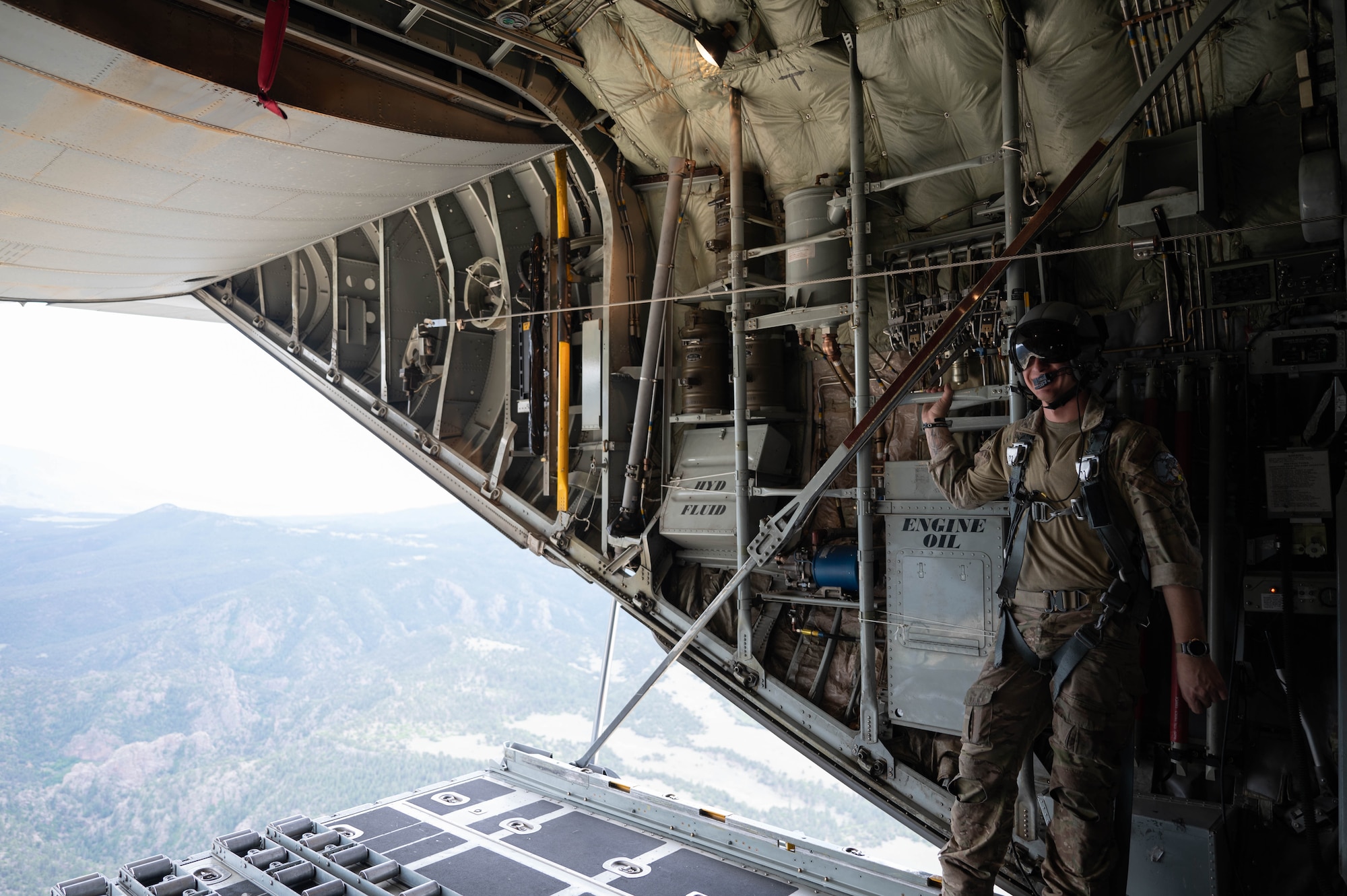 Senior Airman Coale Gonzalez, stand on the open ramp of the C-130 Hercules while in flight.