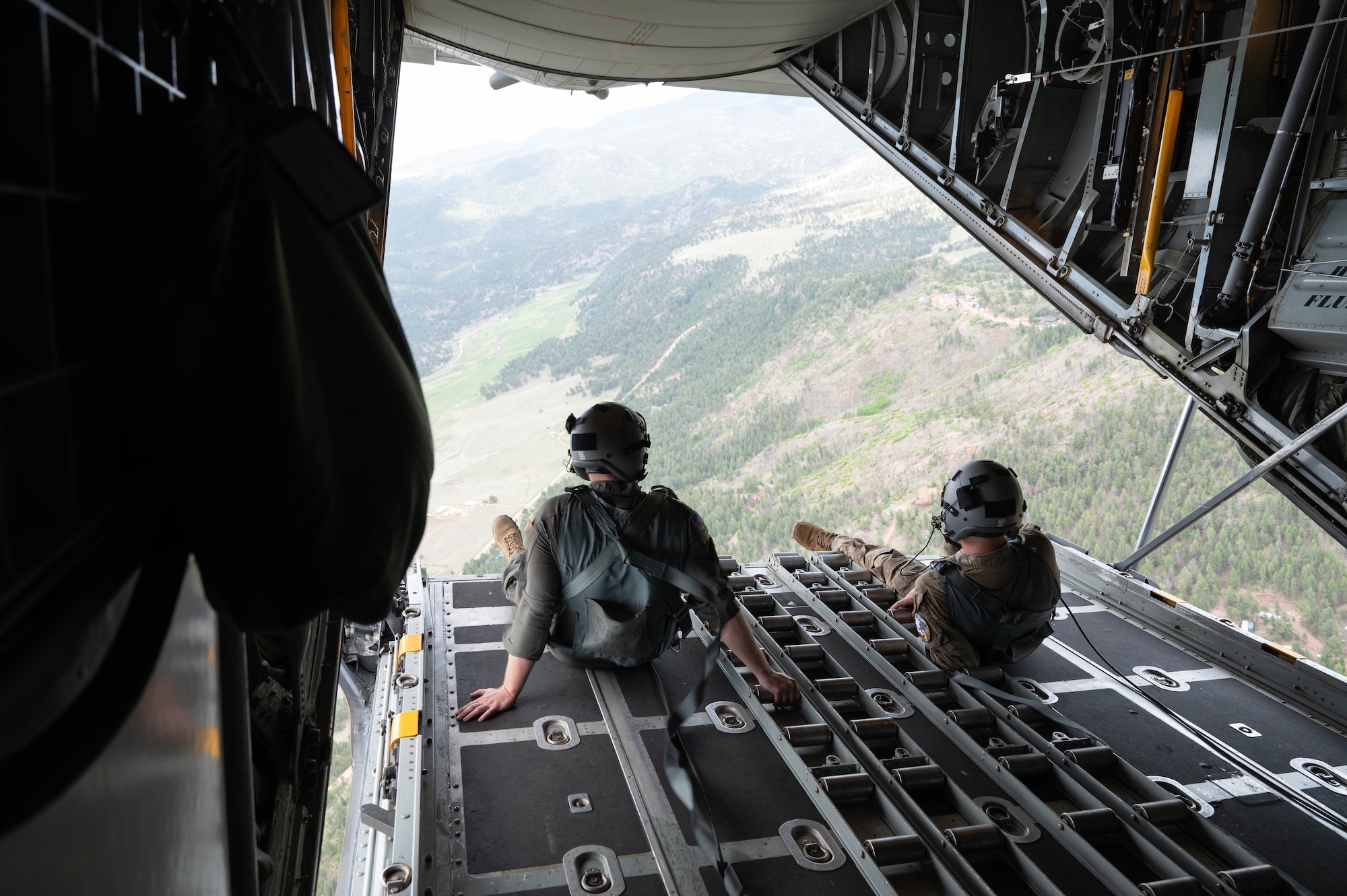 Both loadmaster are sitting on the lower ramp that is open while in flight.