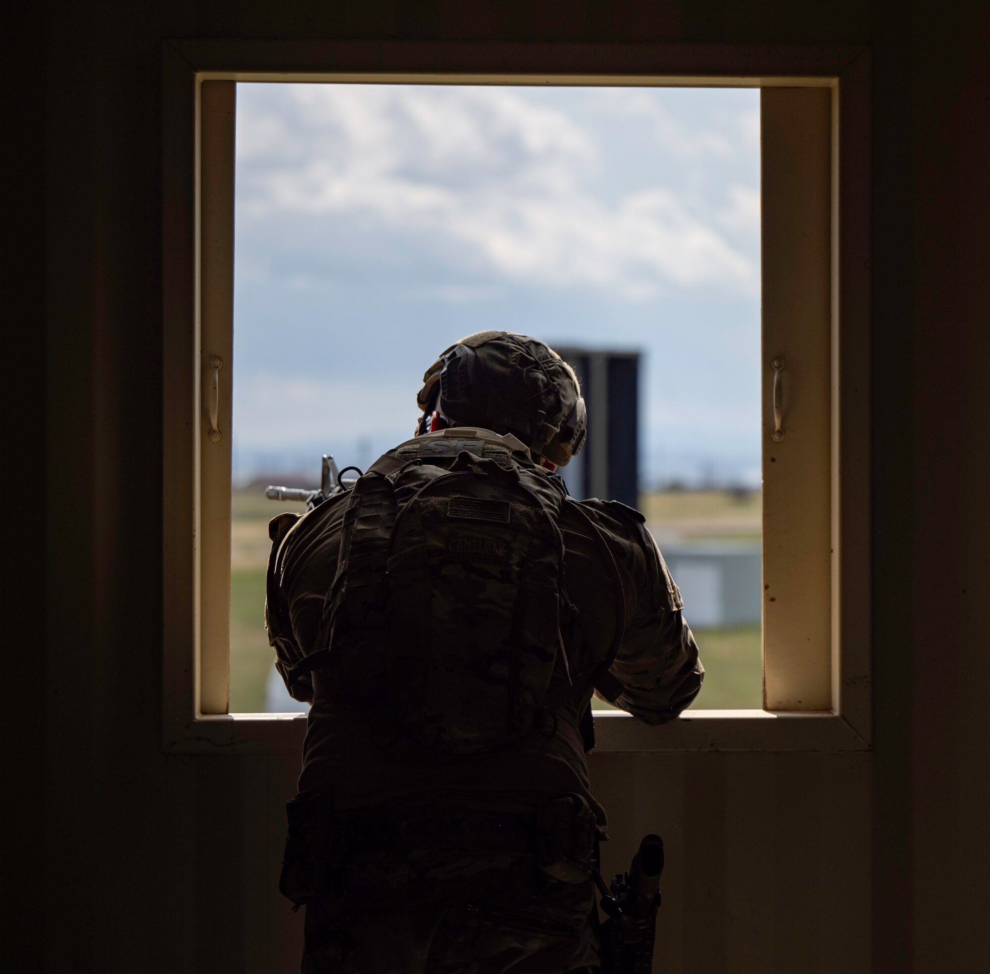 U.S. Air Force Senior Airman Addison Westergren, a 28th Security Forces patrolman, guards a window vantage point during an urban village scenario in a Cerberus Defender exercise at Ellsworth Air Force Base, S.D., 18 July, 2024. This scenario tested Airmen’s execution of the Military Decision-Making Process, a foundational concept to sharpen judgment in high-intensity defense positions. (U.S. Air Force photo by Senior Airman Josephine Pepin)