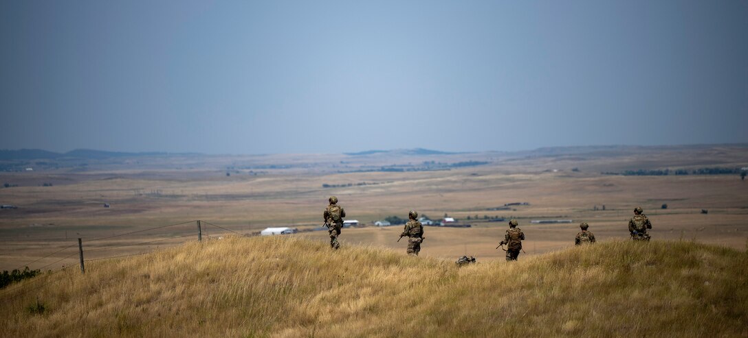 U.S. Airmen from the 28th Security Forces Squadron conduct a patrol for a downed Unmanned Aerial System (UAS) during a Cerberus Defender exercise at Ellsworth Air Force Base, S.D., 18 July, 2024. This part of the exercise focused on small-unit tactics training and communication in the field and included an ambush from enemy fire. (U.S. Air Force photo by Senior Airman Josephine Pepin)