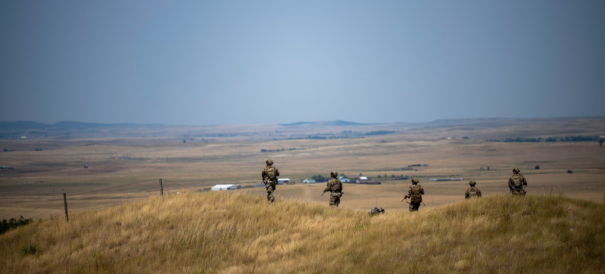 U.S. Airmen from the 28th Security Forces Squadron conduct a patrol for a downed Unmanned Aerial System (UAS) during a Cerberus Defender exercise at Ellsworth Air Force Base, S.D., 18 July, 2024. This part of the exercise focused on small-unit tactics training and communication in the field and included an ambush from enemy fire. (U.S. Air Force photo by Senior Airman Josephine Pepin)