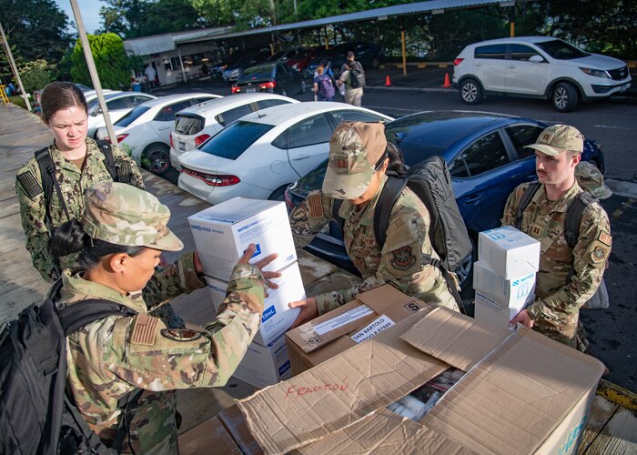 U.S. service members organize boxes in a parking lot.