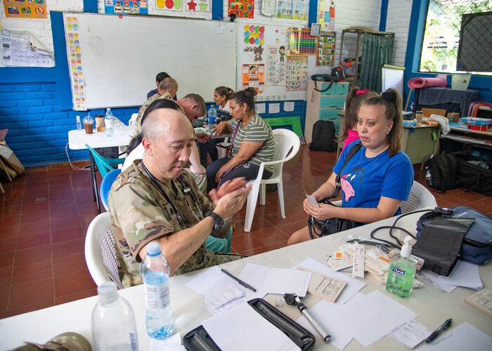 U.S. servicemembers take care of patients in a school classroom.