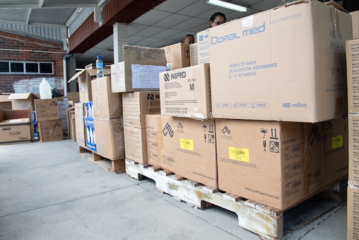Boxes on pallets labeled with the names of medical supplies sitting on the concrete.