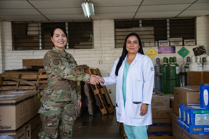 A woman in U.S. military uniform shakes hands with a doctor in civilian clothes.