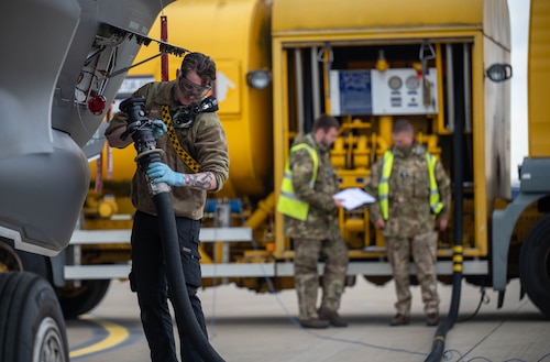 An Airman attaches a fuel hose to an aircraft