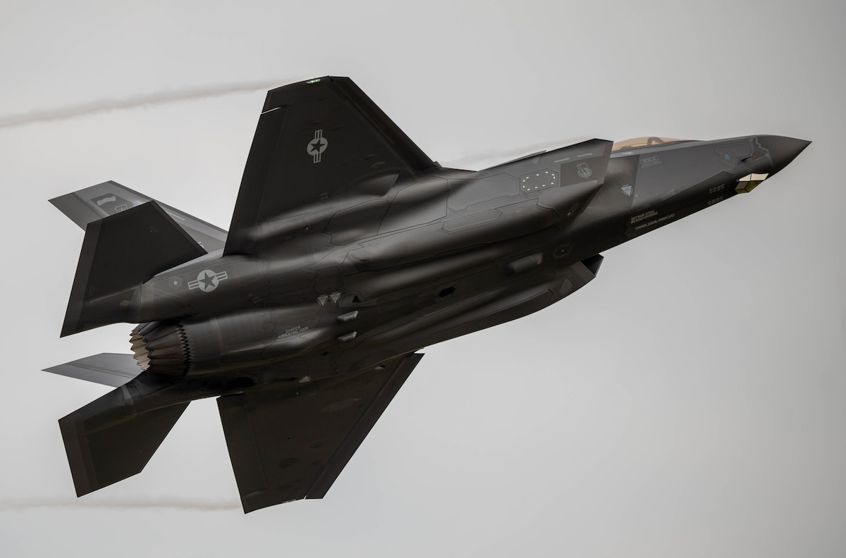 An F-35A Lightning II flies over a grey sky
