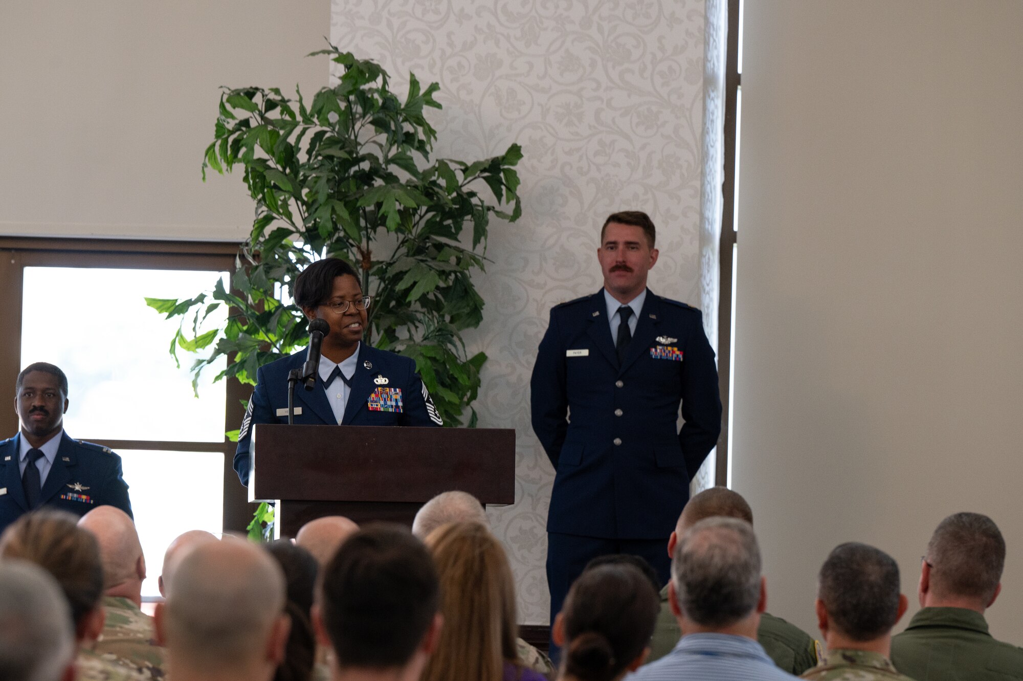 Hert stands at a podium, speaking to the audience