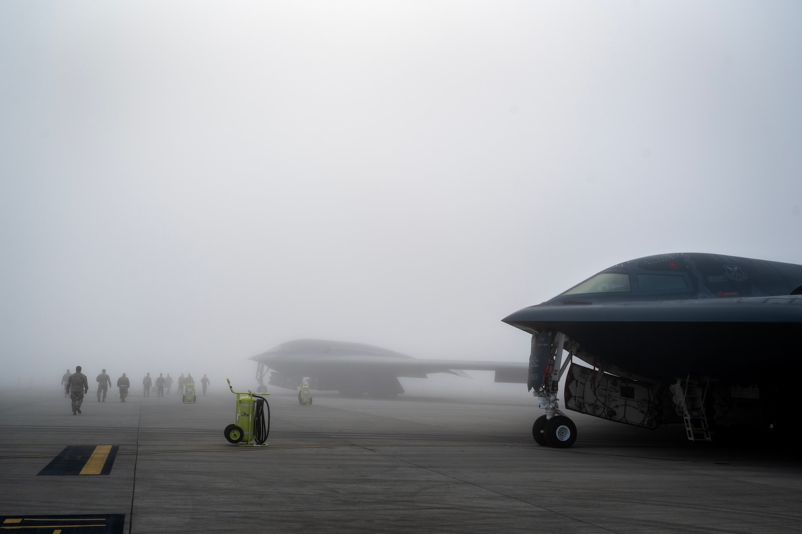 U.S. Air Force Airmen assigned to the 110th Expeditionary Bomb Squadron pass B-2 Spirits as they walk on the flightline