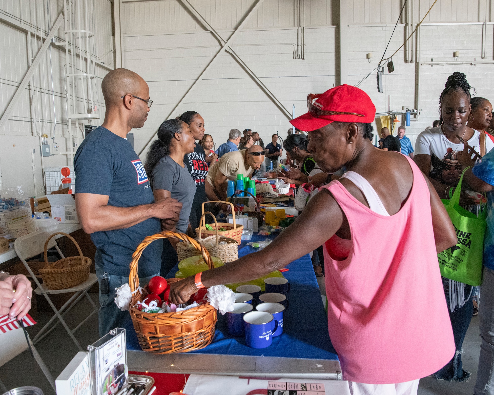People take various items from vendor booths inside a hangar.