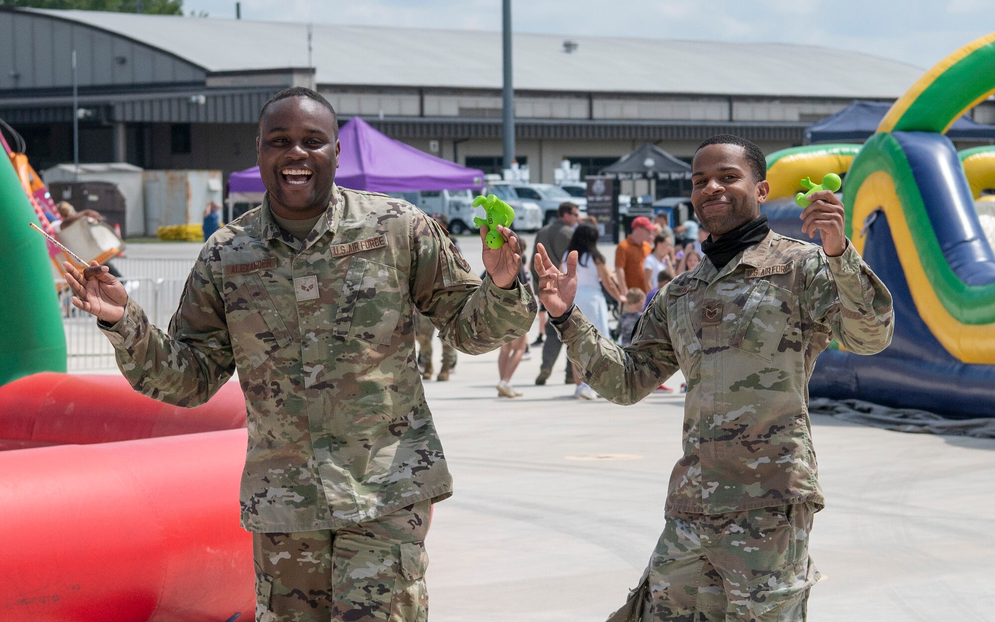 Two airmen pose for a photo while holding up toys.