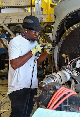 Fleet Readiness Center East (FRCE) sheet metal mechanic Marshawn Becton conducts maintenance on a V-22 Osprey at the depot.