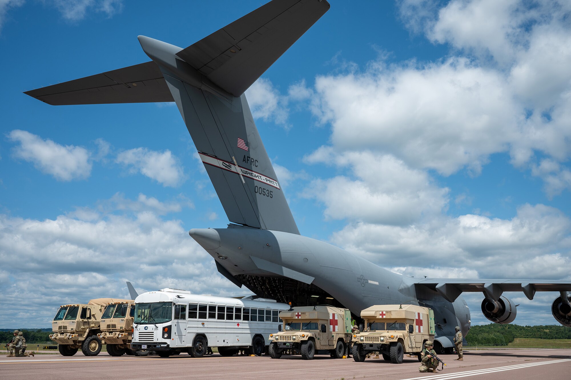 A medical convoy consisting of U.S. Air Force, joint and allied medical personnel participating in Exercise Patriot Medic 2024 line up ambulances to a 445th Airlift Wing C-17 Globemaster III assigned to Wright-Patterson Air Force Base for patient loading and unloading at Fort McCoy Army Airfield, Wisconsin, Aug. 10, 2024. Patriot Medic leveraged specialized training opportunities and partnerships with other military branches and allies to develop combat-ready medics. (U.S. Air Force photo by Tech. Sgt. Timothy Leddick)