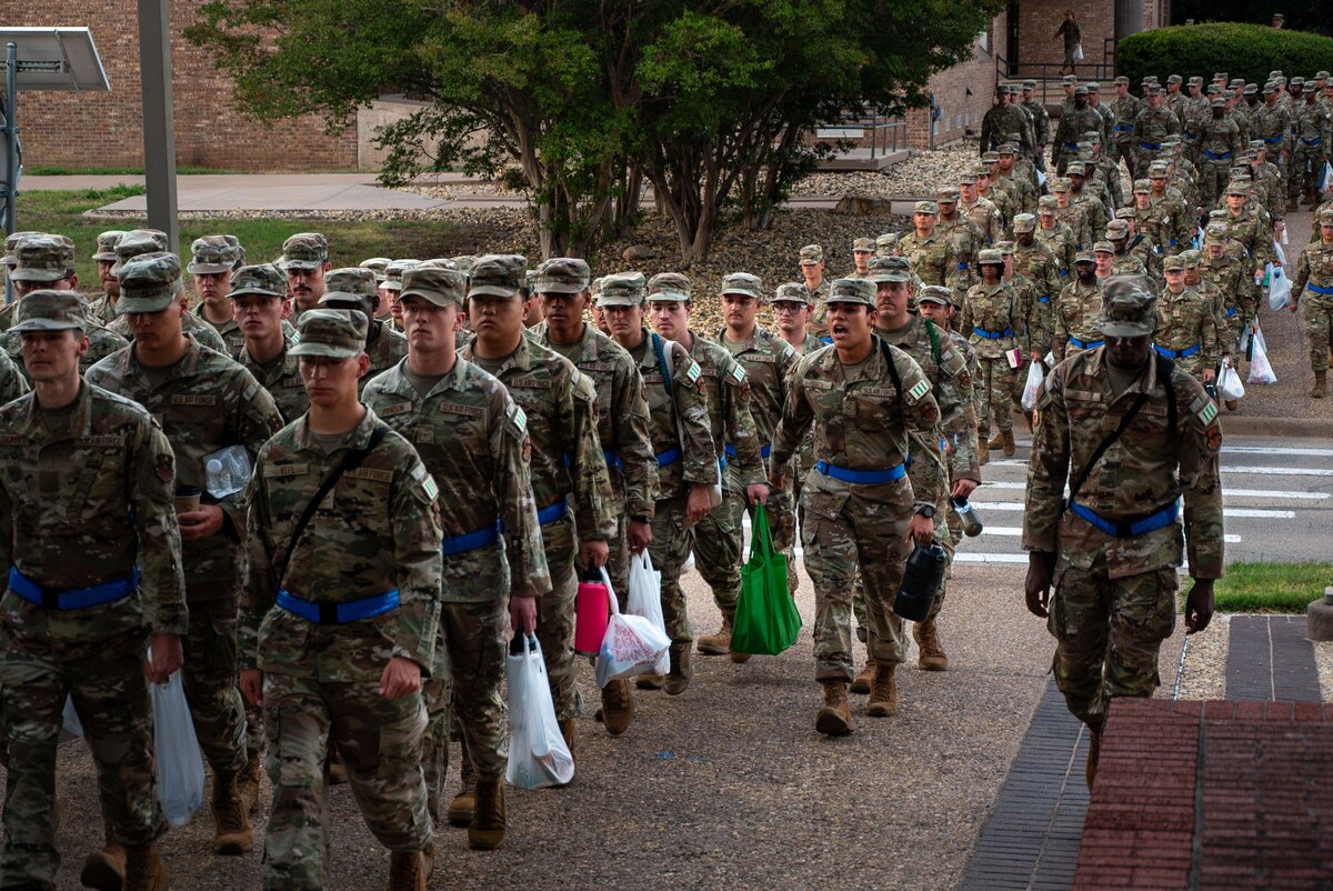 U.S. Air Force Airman 1st Class Lauro Garza, student leader assigned to the 315th Training Squadron, calls cadences while students march to class at Goodfellow Air Force Base, Texas, July 29, 2024. The troopwalk at Goodfellow allows student leaders to use precise facing movements to keep their flights aligned with the winding path from the dorms to the schoolhouse. (U.S. Air Force photo by Airman 1st Class Brian Lummus)