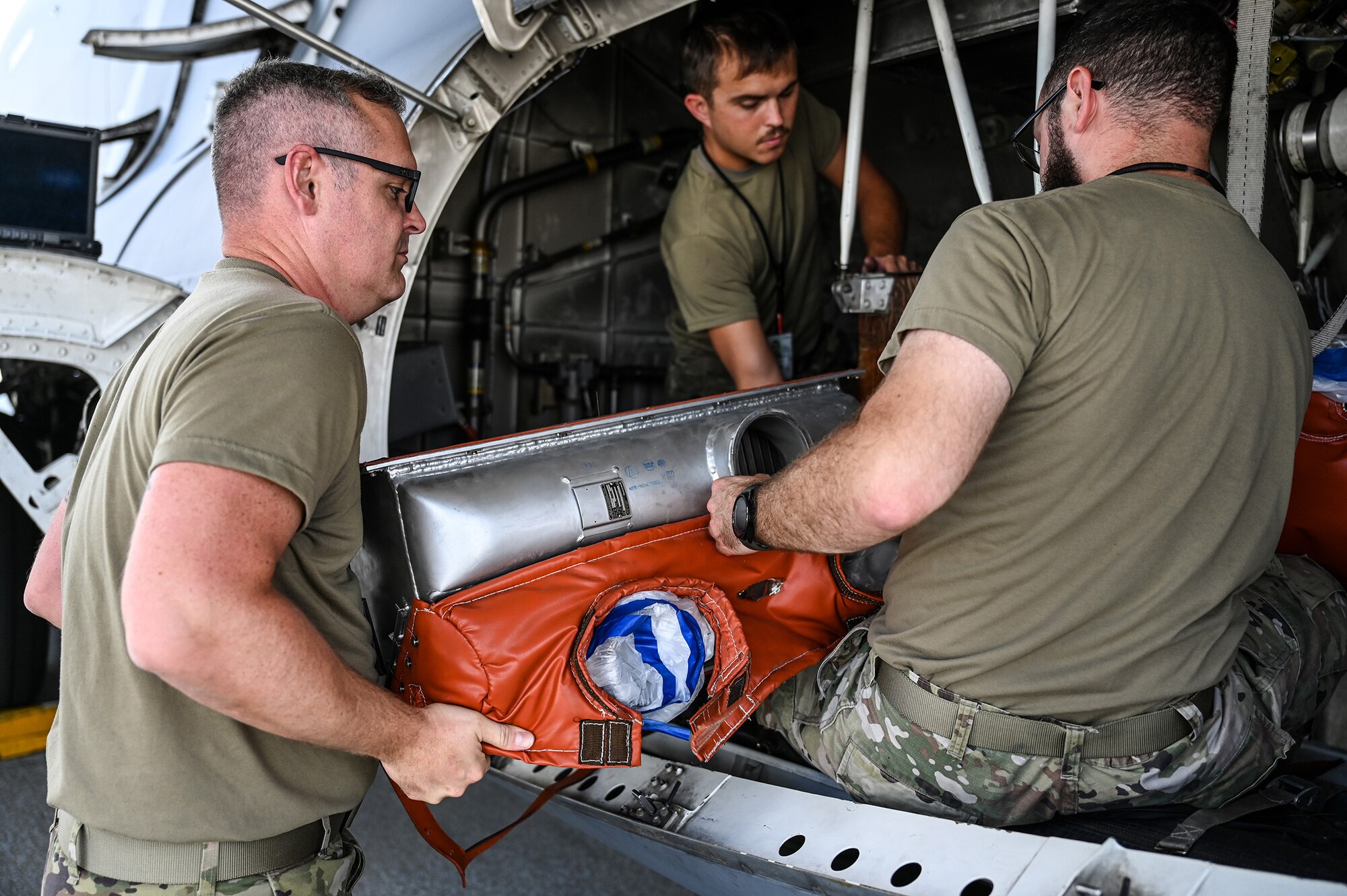 (from left to right) Tech. Sgt. Sean Steele, Senior Airman Paul Watkins and Tech. Sgt. Chris Lewis, 445th Aircraft Maintenance Squadron electrical and environmental technicians, remove a heat exchanger from a C-17 Globemaster III at Wright-Patterson Air Force Base, Ohio, Aug. 3, 2024. Heat exchangers are used in both cooling and heating processes in the aircraft.