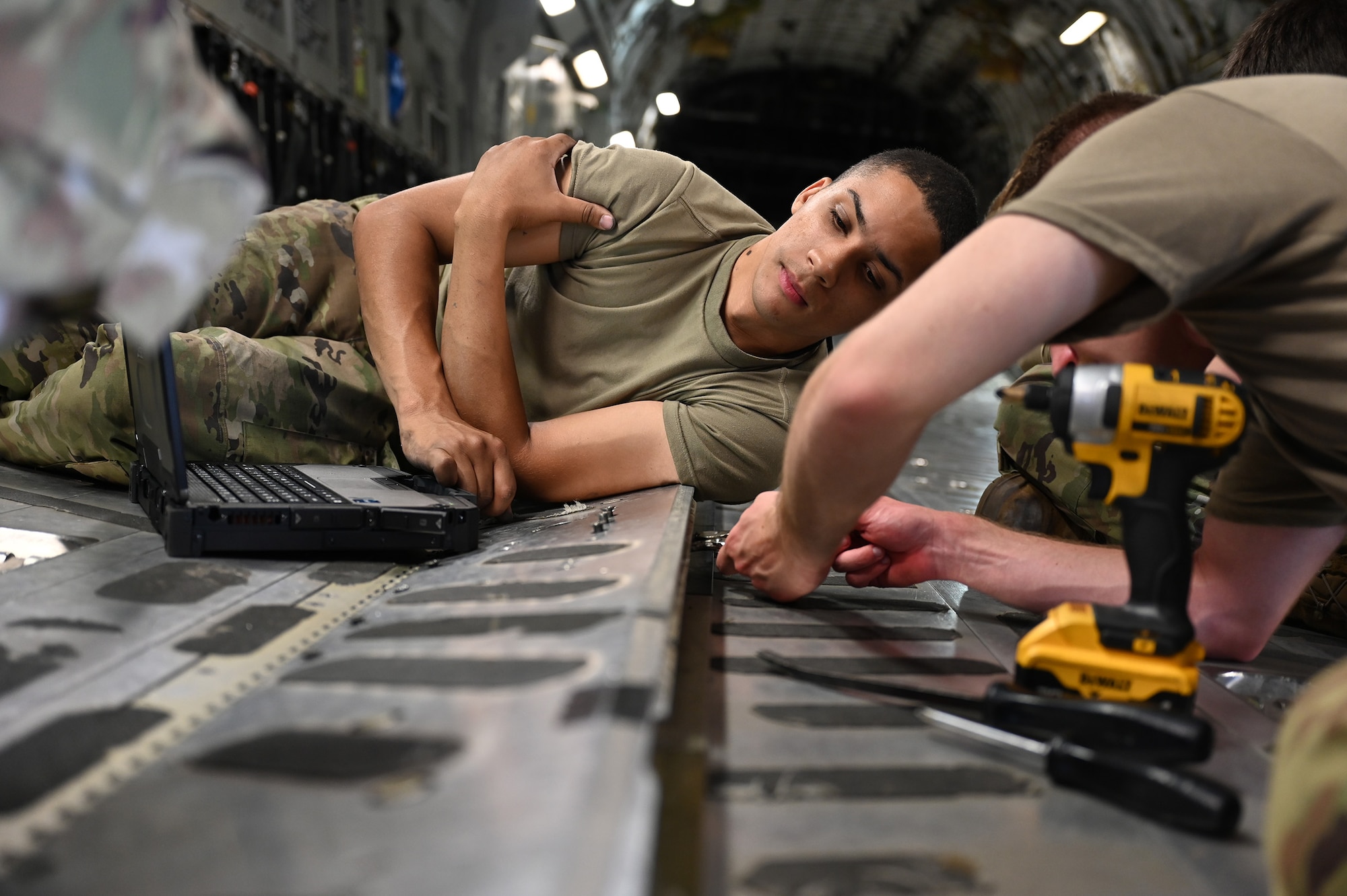 (from left to right) Senior Airmen Jorden Terry and Jonathan Zimpfer, 445th Aircraft Maintenance Squadron crew chiefs, work on a broken variable restraint assembly on a C-17 Globemaster III at Wright-Patterson Air Force Base, Ohio, Aug. 3, 2024. Broken aircraft items like this one are not only repaired by the Airmen but also used as a training tool for new crew chiefs in the unit.