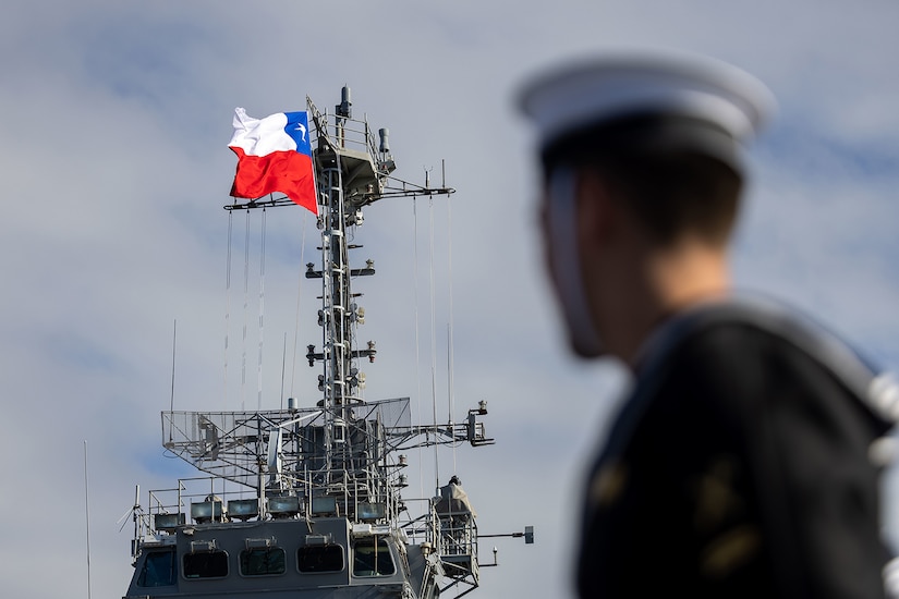 A service member looks at a ship during daylight.