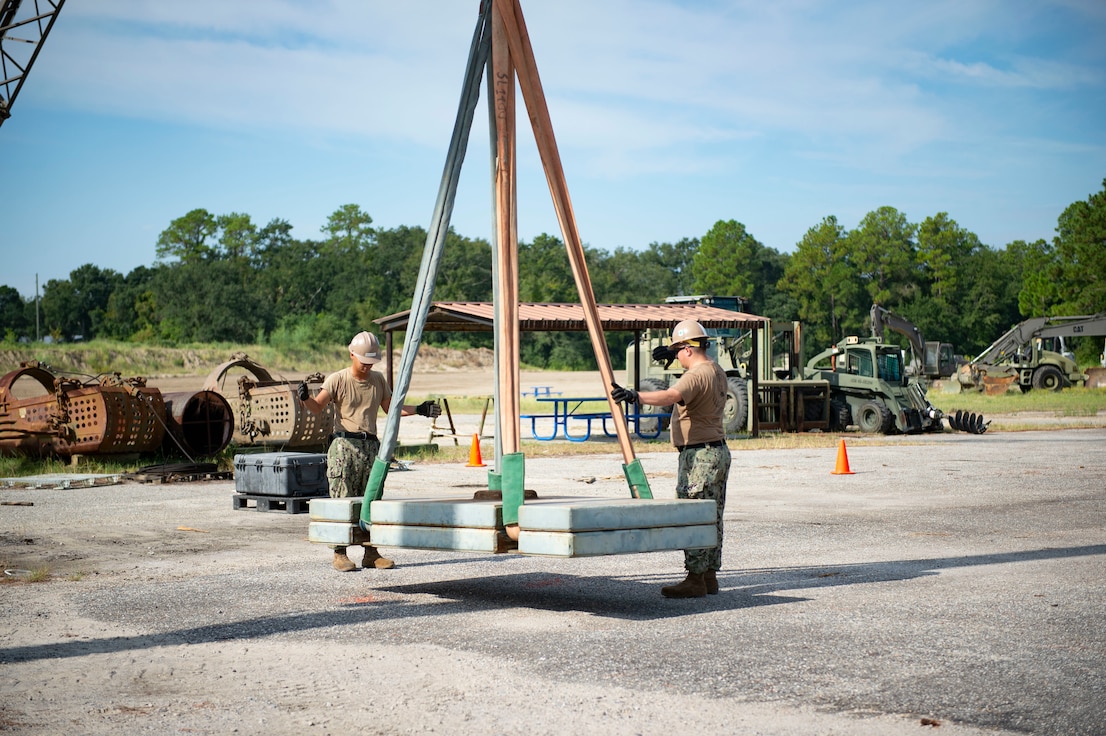 Equipment Operator 3rd Class Lyncoln KestlerReyes, left, and Equipment Operator 1st Class Colton Magee, assigned to Naval Mobile Construction Battalion 133 (NMCB 133), direct a lift as part of a crane certification on Naval Construction Battalion Center, Gulfport, Mississippi, August 27, 2024.