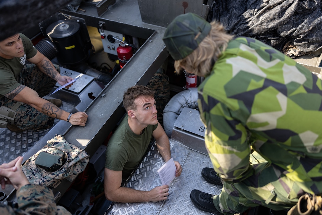 U.S. Marine Corps Sgt. Jonathan Ebel, assault amphibious vehicle technician, listens to instructions from a Swedish service member during a CB90 combat boat starting procedure class at Berga Naval Base, Sweden, Aug. 28, 2024. Marines assigned to 4th Assault Amphibian Battalion, 4th Marine Division, Marine Forces Reserve, are deployed for training in support of Exercise Archipelago Endeavor, an annual integrated, Swedish Armed Forces-led exercise that increases operational capabilities between U.S. Marines and Swedish forces. (U.S. Marine Corps photo by Sgt. Scott Jenkins)