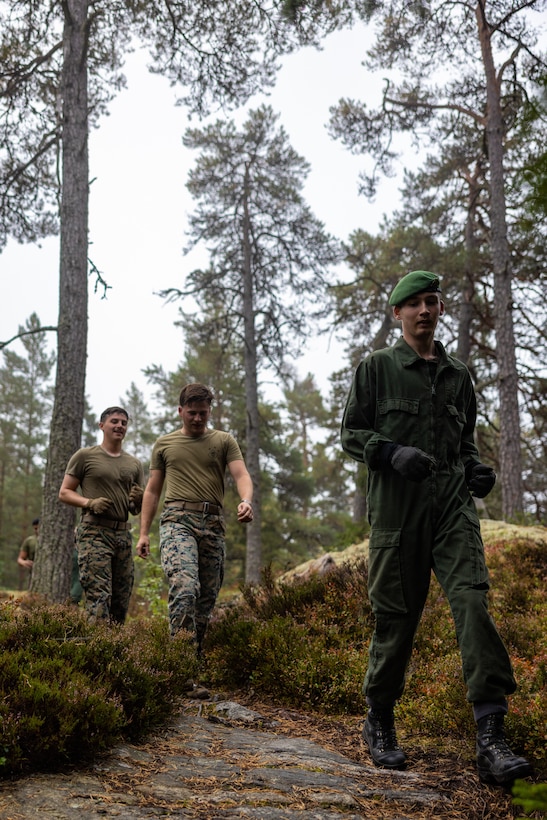 A Swedish service member leads a group of U.S. Marines down a hill side during an obstacle course at Berga Naval Base, Sweden, Aug. 30, 2024. Marines assigned to 4th Assault Amphibian Battalion, 4th Marine Division, Marine Forces Reserve, are deployed for training in support of Exercise Archipelago Endeavor, an annual integrated, Swedish Armed Forces-led exercise that increases operational capabilities between U.S. Marines and Swedish forces. (U.S. Marine Corps photo by Sgt. Scott Jenkins)