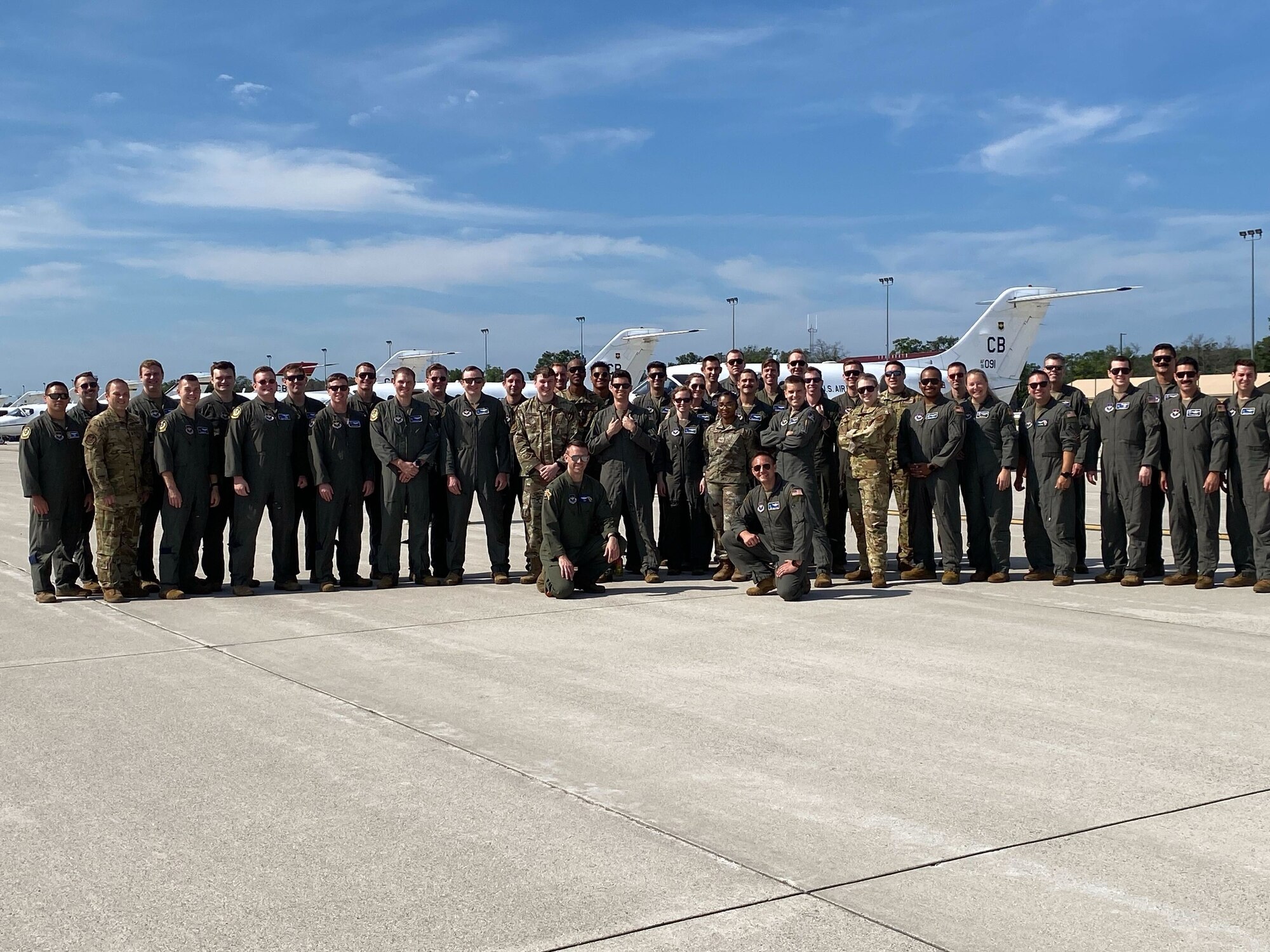 Service members from Columbus Air Force Base pose in front of aircraft during their training in Michigan.