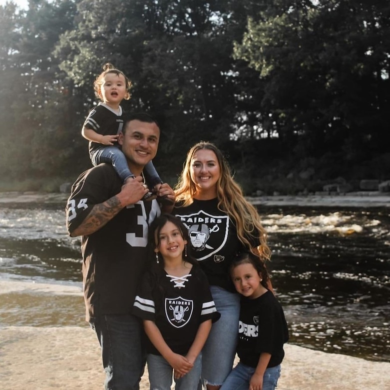 Family portrait of father, mother, and three daughters wearing Raiders gear