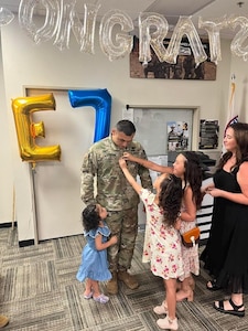 U.S. Army Soldier at promotion ceremony, getting promoted by his wife and three daughters