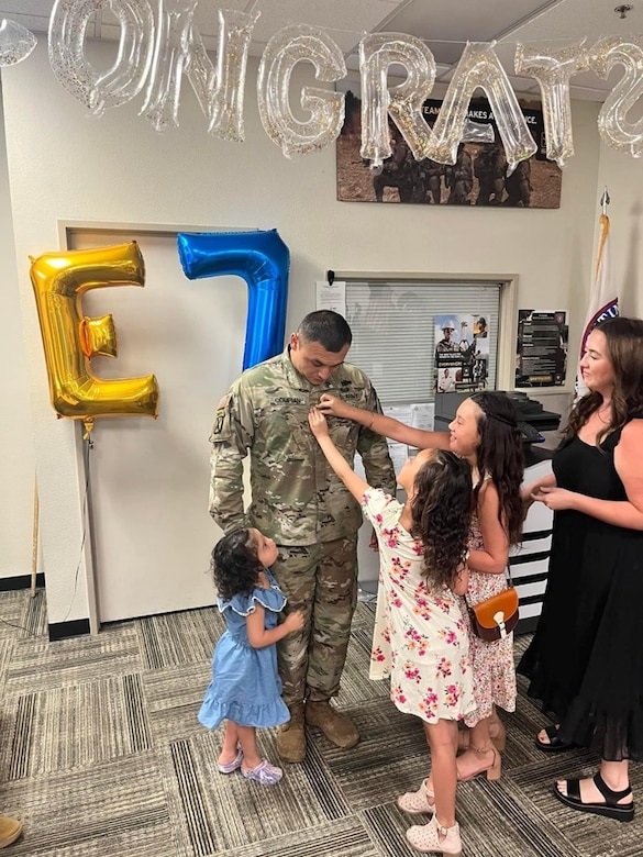 U.S. Army Soldier at promotion ceremony, getting promoted by his wife and three daughters