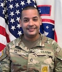 U.S. Army Soldier in uniform poses in front of the American Flag and USAREC Flag for official headshot