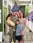 U.S. Army Soldier in uniform poses with wife, son and daughter in front of an American Flag and a USAREC Flag.