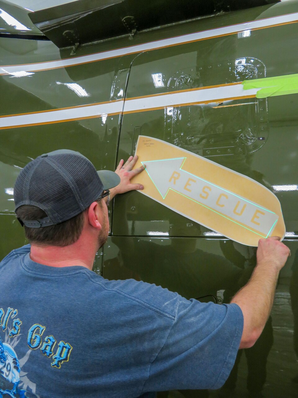 Ben Davidson, aircraft painter for the Fleet Readiness Center East Aircraft Paint Shop, uses the laser projection system to mask rescue arrows onto a MV-22B Osprey flown by the Marine Helicopter Squadron. The laser projection system acts as a guide for the precise placement of markings and insignia on aircraft during the final finish process.