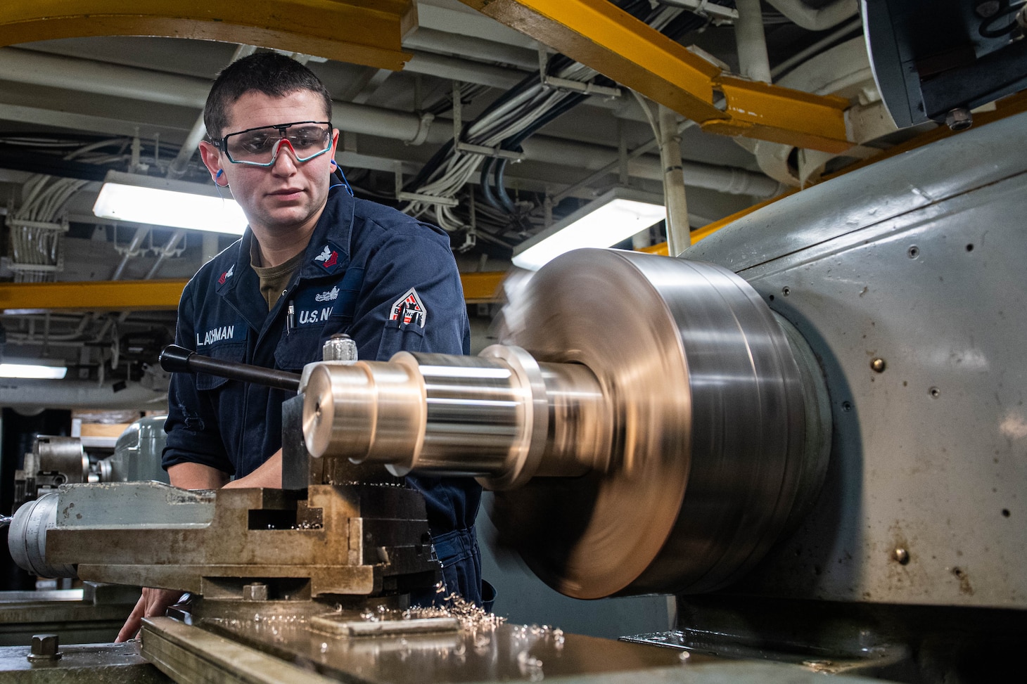 240604-N-ER894-1095 PHILIPPINE SEA (June 4, 2024) Machinery Repairman 1st Class Adam Lachman, from East Meadow, New York, operates a lathe to turn a piece of steel in the machine repair shop aboard the U.S. Navy’s only forward-deployed aircraft carrier, USS Ronald Reagan (CVN 76), in the Philippine Sea, June 4. Ronald Reagan, the flagship of Carrier Strike Group 5, provides a combat-ready force that protects and defends the United States, and supports alliances, partnerships and collective maritime interests in the Indo-Pacific region.