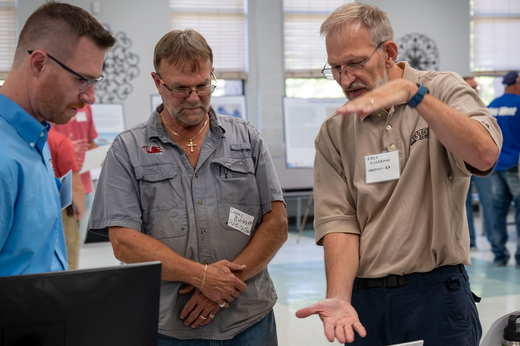 Three men discuss a visual aid.